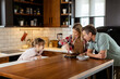 © BGStock72 - Joyful Family Enjoying Homemade Chocolate Cake in Cozy Kitchen