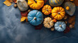 A group of pumpkins with dried autumn leaves and twig, on a blue color stone