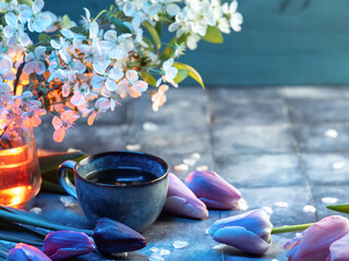 Wall Mural - A cup of coffee on the table with a bouquet of tulips and a blooming white cherry, copy space