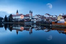 Telc town - night city in Czech republic with moon on sky and lake on foreground