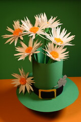 Green Saint Patrick's hat with daisy flowers on green and orange background