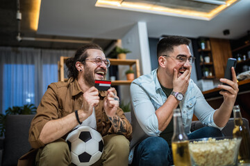 Two friends online betting on soccer with their credit card.