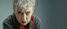 Frowning Senior Woman. Angry Belligerent Senior Woman Looking At The Camera. Portrait Of A Angry Grandma. Senior Grey-haired Woman Wearing Casual Clothes Skeptic And Nervous.