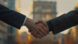 Two businessmen finalize a lucrative business agreement with a handshake, captured in close-up, with city buildings blurred in the background