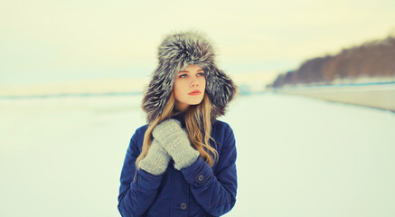 Wall Mural - Portrait of beautiful blonde young woman posing in winter hat outdoors