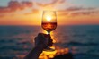 © piai - A hand holding a glass of wine, sunset background