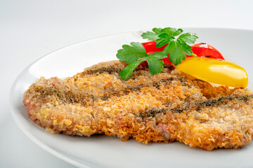 Golden fried breaded chicken schnitzel in a plate on a white background, chicken chop dishes