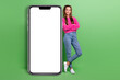 © deagreez - Full size photo of positive girl wear pullover hold arms crossed near smartphone display empty space isolated on green color background