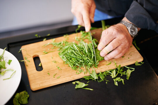 hands, salad and chopping board with a man and green leaves for cooking health food in a home. nutri