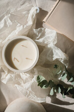Overhead View Of A Candle, Books, Wrapping Paper And Eucalyptus Stems On A Table