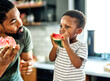 © Lumos sp - child family kitchen food boy son father mother watermelon fruit slice summer organic meal fun preparing healthy diet eating home black
