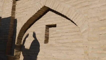 Wall Mural - Shadow of woman dancing on the wall in old city of Uzbekistan