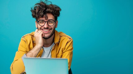 Poster - In his glasses, a friendly millennial guy uses his laptop computer for online communication and work on a blue studio background.