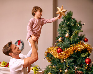 Wall Mural - Father, son and happy with bonding by christmas tree for celebration and playing with star in the morning. Family, man and child with smile, relax and enjoying holiday season with decoration in home