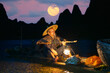 © Revive Photo Media - Traditional Chinese cormorant fisherman illuminated by his flaming (petrol) lantern quietly smoking a pipe at night in his bamboo boat at the end of his day's work on the Li River with full moon