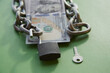 © Александр Ланевский - Hundred-dollar bills with a chain on them and an open lock and key nearby on green cloth, unlocking funds, unlocked money, unlocking an account