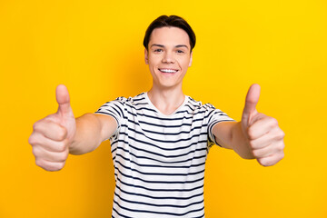 Poster - Portrait of satisfied student with brunet hair wear stylish t-shirt showing thumbs up to you isolated on vibrant yellow color background