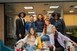 © JoseIMartin - Diverse group of professionals smiling and posing together in a modern office lounge, showing team spirit and collaboration.