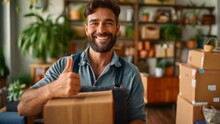 The Concept Of Moving Day A Happily Smiling Employee Providing Overall Moving Services Stood In The Living Room Of The New House, Holding A Cardboard Box And Giving A Thumbs Up.