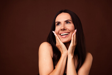 Wall Mural - Photo of positive cute surprised girl touch soft flawless smooth no filters skin look empty space isolated on brown color background