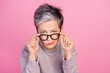 Photo of charming retired woman hold glasses suspiciously looking watching camera isolated on pink color background