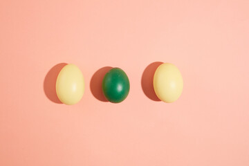 Wall Mural - Photographed from above, yellow and green Easter eggs hand painted displayed on a pink background. Easter eggs have many meanings: fertility, proliferation and good luck