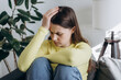 © Yura Yarema - Close up of nervous young caucasian woman sitting alone on couch at home feeling sad tired and worried suffering depression in mental health, feels guilt, makes difficult decision concept