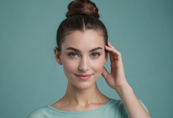 Wall Mural - A stylish woman in a casual pose touching her hair, wearing a light teal top against a blue background.