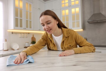 Sticker - Woman with microfiber cloth cleaning white marble table in kitchen