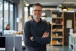 © sambath - portrait of a smiling man, standing in hero-pose, head in shoulders in frame, standing for a officeroom,