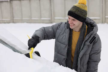 Wall Mural - Man cleaning snow from car windshield outdoors