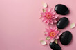 Two vibrant pink water lilies and black spa stones on a soft pink background with copy-space, symbolizing tranquility.