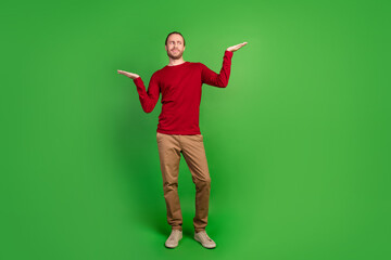 Wall Mural - Full size photo of minded confused man dressed red pullover look at worse option on arm empty space isolated on green color background