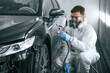 © standret - Professional worker. Man is painting a car by using spray guy