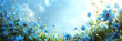 A panoramic spring background is formed as forget-me-not flowers bloom in a meadow under the sunny light