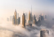 © AmazingAerialAgency - Aerial view of Burj Khalifa and Downtown Dubai surrounded by hazy clouds, Dubai, United Arab Emirates.