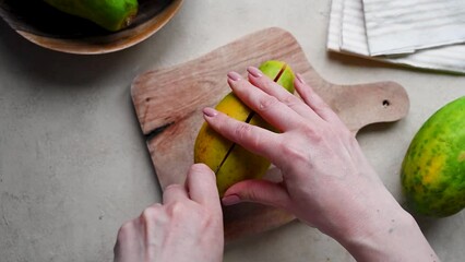 Wall Mural - Papaya fruit, female hands cutting in halves fresh papaya, top view