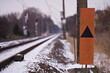 Znak kolejowy obok torów pokrytych śniegiem w zimowy dzień