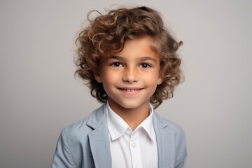 Portrait of a cute little boy with curly hair over grey background