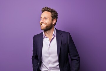 Wall Mural - Portrait of a handsome young man in a suit on a purple background.