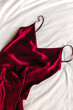 Red silk dress lying on the bed, overhead view