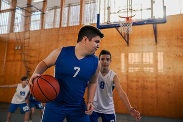 Wall Mural - Active junior basketball player in action guarding a ball during game.