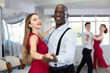 © JackF - Positive elegant black man enjoying slow foxtrot with stylish female partner in red dress in dance studio. Amateur social dancing concept..