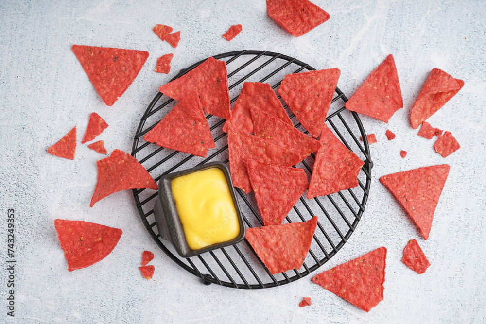 Tray with red nachos and cheese sauce on blue grunge background
