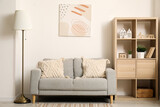Fototapeta Panele - Interior of modern living room with comfortable sofa, lamp, picture and shelves