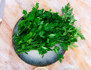 Wall Mural - Fresh green parsley twigs on plate on wooden kitchen table.