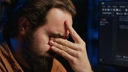 Disappointed computer scientist puzzled after being unable to remove all bugs while coding on workstation desktop. Teleworking IT specialist confused by troubling script errors, camera A close up