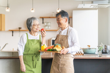 Poster - 家のキッチンの前で笑顔で話すアジア人高齢者夫婦（料理教室）
