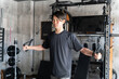 ジム・トレーニングジムでパワーラックのケーブルを使って胸の筋トレをする若いアジア人男性
