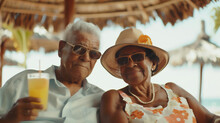 Happy elderly couple enjoying tropical beach vacation, holding refreshing drinks under a straw hut